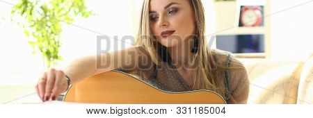 Woman Practice Acoustic Guitar Playing At Home. Female Player Performing While Sitting On Couch In L