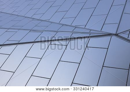 Angular View Of Metal White Tiles With Blueness Shade On Wall Of Building With Geometric Design