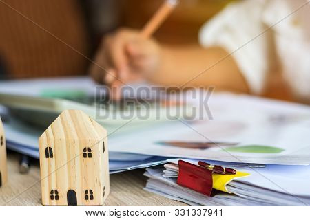 Closeup Of Home And Businesswoman Use Calculator For Analyzing Data Of Market Report For Loan Home.