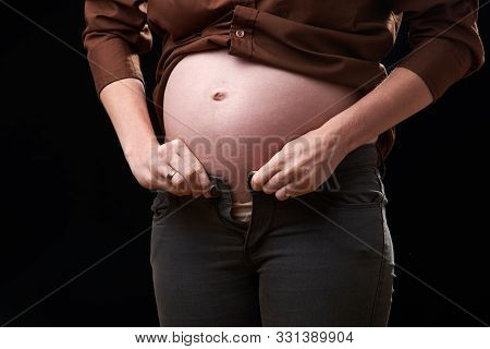 The Inconvenience Of Pregnancy. A Pregnant Woman Cant Fasten Her Pants. Gravity Of Movements Of The 