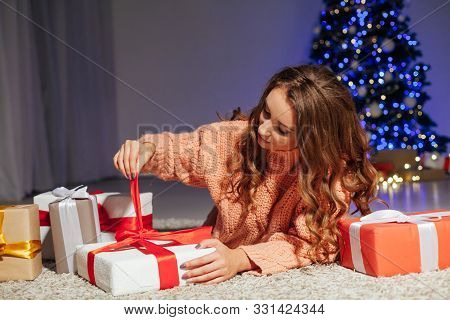 Beautiful Woman Opens Gifts At The Christmas Tree At Night At Home New Year Lights Garlands