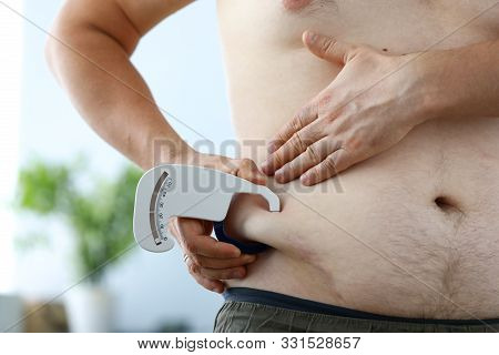 Close-up Of Male Hand Holding Special Metering Fitness Utility Using To Look At Overweight Side Of B