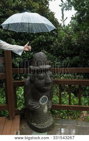 Jeju Island, South Korea, September 08, 2019: Mans Hand Is Holding His Umbrella Over Dol Hareubang S