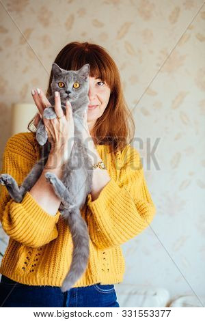 Vertical Close Up Portrait Of Lovely Middle-aged Redhead Woman With Gray Cat At Home. Mature Female 