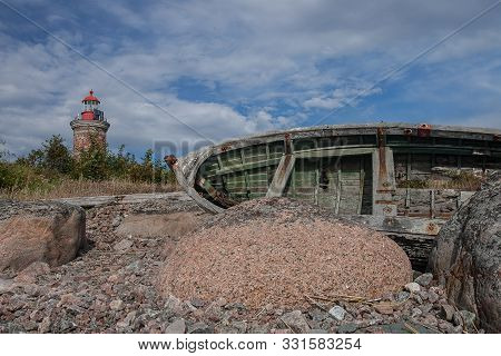 Lighthouse And Old Boat In The Baltic Sea. Shore, Evening Light, Sunset, Clouds And Architecture Con