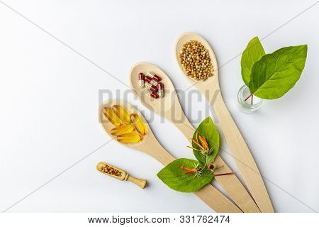 Herbal Capsule, Natural Vitamins, Dry Calendula Flowers At Wooden Spoon On White Background. Concept
