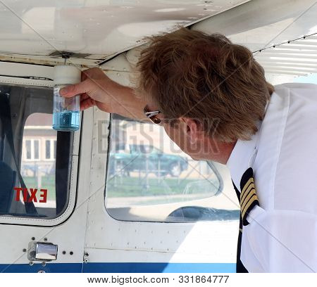 Flight Instructor In Uniform Doing Pre-flight Check Testing Fuel Before Lesson - Safety First Concep