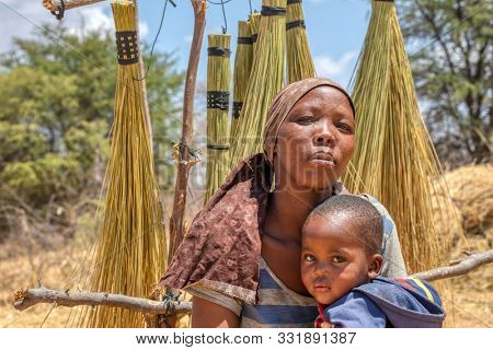 African woman with a child in a village in  Botswana standing in front of  the bush in Kalahari , Botswana