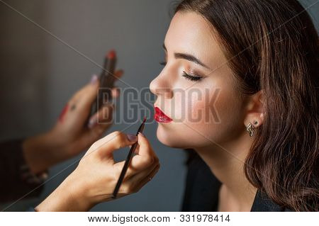Makeup Artist Applies Red Lipstick To A Young Beauty. Girl Do Make-up