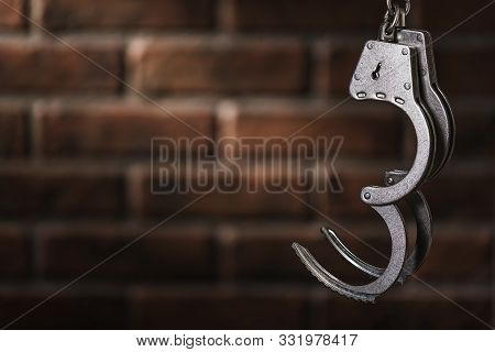 Open Handcuffs Against The Background Of A Brick Wall With A Copy Of The Space. Concept: The Price O