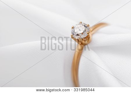 Beautiful Gold Engagement Ring With A Diamond On A Silk Fabric With Copy Space, Close-up