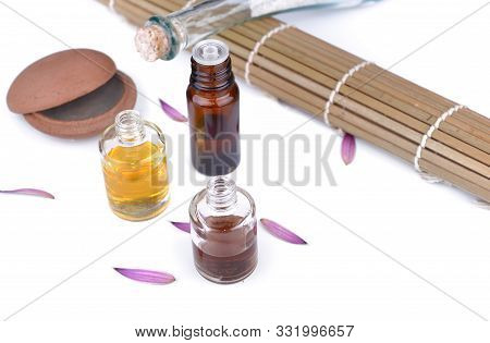 Bottles Of Essential Oil And Massage Balm With A Bambou Mat On White Background
