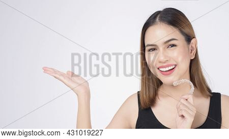 Young Smiling Woman Holding Invisalign Braces In Studio, Dental Healthcare And Orthodontic Concept