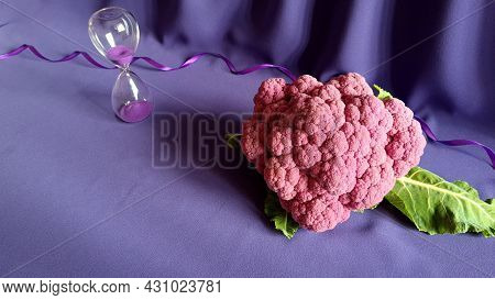 Hourglass And Cauliflower On Purple Background With Wavy Ribbon