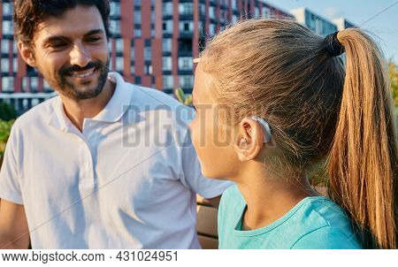 Positive Female Child With A Hearing Impairment Uses A Hearing Aid To Communicate With Her Father Ou