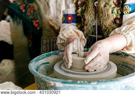 A Woman In Traditional Slavic Clothes Works On A Potter's Wheel. Master Woman Works In A Traditional
