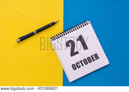 October 21th. Day 21 Of Month, Calendar Date. Notebook With A Spiral And Pen Lies On A Yellow-blue B