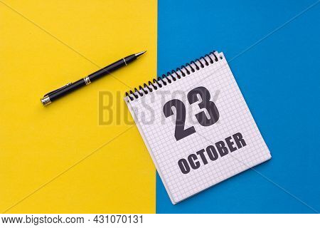 October 23th. Day 23 Of Month, Calendar Date. Notebook With A Spiral And Pen Lies On A Yellow-blue B