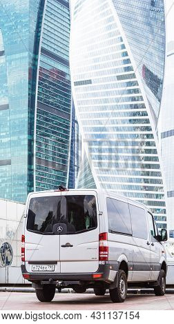 Silver Mercedes-benz Sprinter 319 Cdi Passenger Van Parked In Front Of Modern Skyscrapers. Rear Side