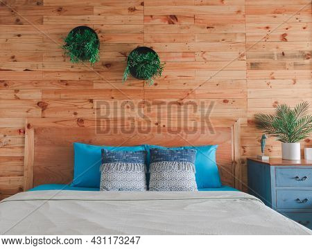 The Wooden Bedroom Interior Features Blue Bedding And Pillows And White Blankets And Potted Plants T