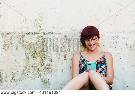 Cheerful Woman Browsing With Her Smartphone On Green Hill