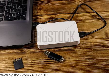 External Hdd Connected To Laptop Computer, Sd Memory Card And Usb Flash Drive On A Wooden Desk. Conc
