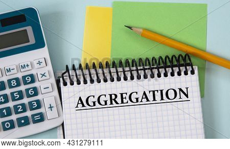 Aggregation - Word In A White Notebook On The Background Of A Calculator, Pencil, Colored Pieces Of 