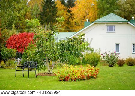 Beautiful Green Garden Full Ot Trees, Decorative Plants And Blossoming Flowers With Big White House