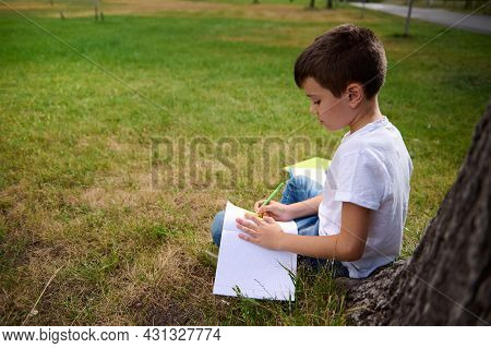 Intelligent Schoolboy Holding Pen , Doing Homework, Writing On Copy Book, Solving Mathematics Tasks,