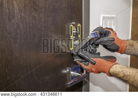 Hands Removing A Deadbolt Cover From A Front Door Lock