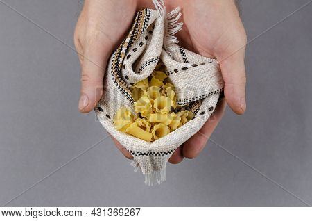 Campanelle, Gigli Or Ballerina Pasta. Dry Uncooked Pasta In Male Hands Against A Gray Background. A 