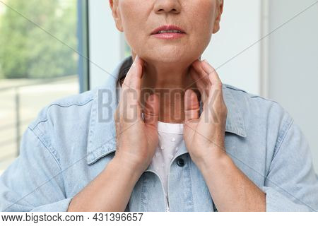Mature Woman Doing Thyroid Self Examination Near Window, Closeup