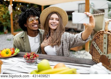 Cool Caucasian Lady And Her Black Boyfriend Having Lunch At Campsite, Taking Selfie Near Rv, Resting