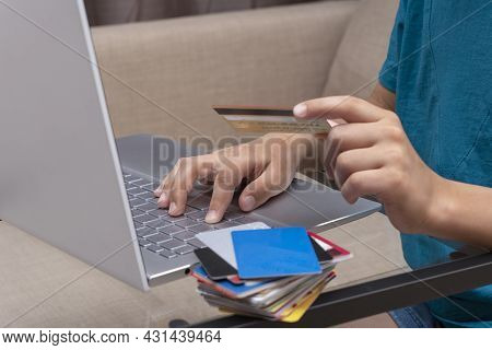 Close Up Image Of Boy's Hands Holding Credit Card And Pressing Buttons On Laptop During Online Payme