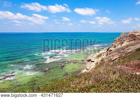 Sea surf with white foam of waves. Apollonia Park, Israel. Mediterranean coast. Picturesque ruins of the medieval citadel of Arsuf