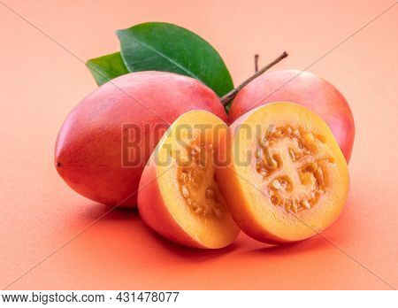 Ripe tamarillo fruits with slices and tamarillo leaves isolated on a orange background.