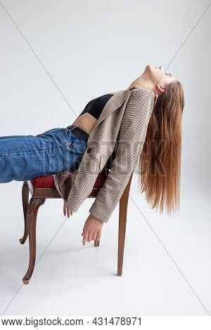 Portrait Of Young Caucasian Woman With Long Hair In Black Top, Blue Jeans And Suit Jacket, Lying On 