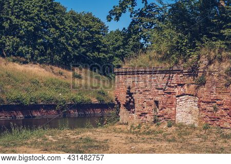 Ruins Of A Brick Walls Building. Old Ruined Fortress By The River Canal And Forest Nearby. Stock Pho