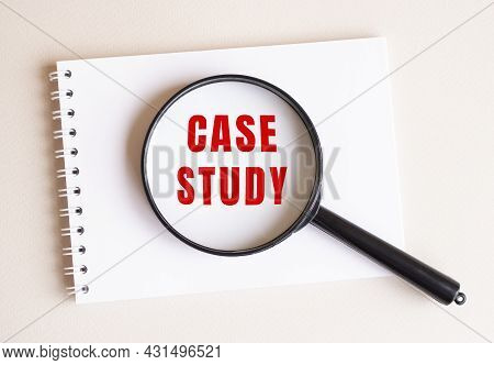 The Magnifying Glass Lies On The Notebook And Shows The Inscription Case Study On A White Page. Busi