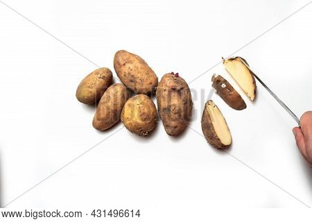 There Are Potatoes On A White Table.next To A Cut Rotten Potato.