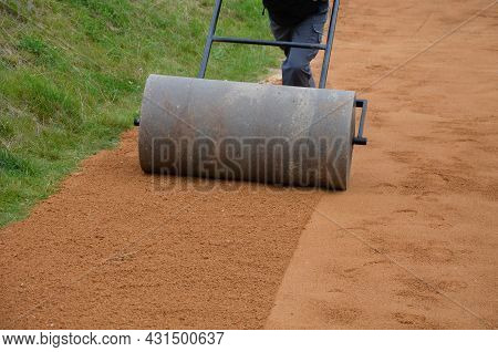 Compressing The Gravel Of The New Park Threshing Path. Lawn Seed Is Repaired By Rolling A Metal Hand