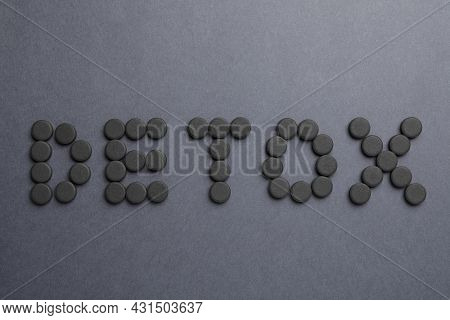 Word Detox Made With Activated Charcoal Pills On Dark Background, Flat Lay. Natural Sorbent