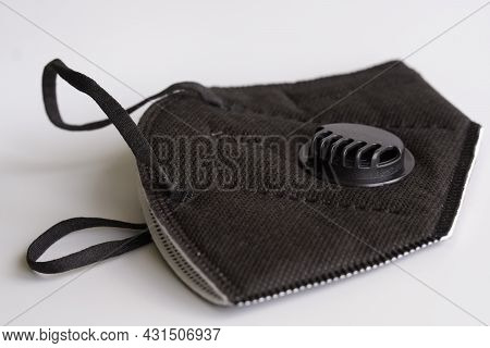 Black Respirator With A Filter And A Valve Lies On A White Background. The Respirator Has A Kn95 Pro