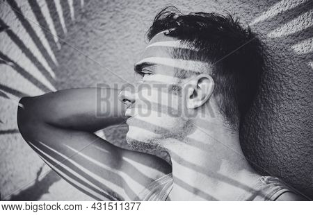 Young man fashion art portrait. Handsome male close up. Black and white portrait of sexy muscular guy posing outside, profile 