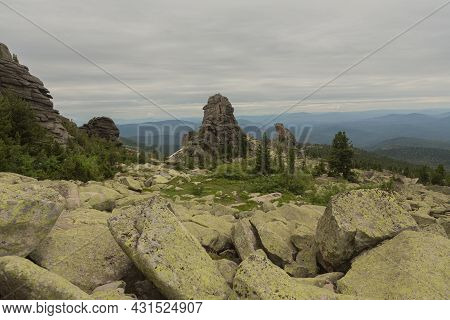 Large Kurum Stones Lie In The Forest In The Mountains, Stones Covered With Moss, Against The Backgro