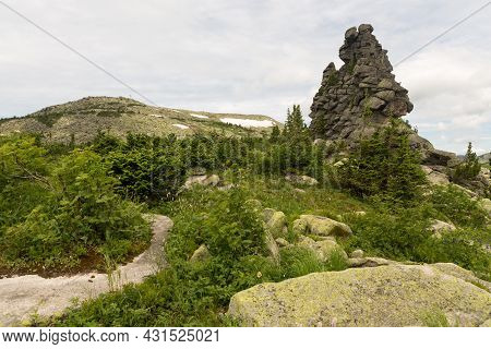 Large Kurum Stones Lie In The Forest In The Mountains, Stones Covered With Moss, Against The Backgro