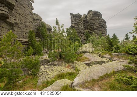 Large Kurum Stones Lie In The Forest In The Mountains, Stones Covered With Moss, Against The Backgro