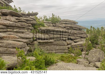 Large Kurum Stones Lie In The Forest In The Mountains, Stones Covered With Moss, Against The Backgro
