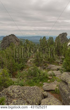Large Kurum Stones Lie In The Forest In The Mountains, Stones Covered With Moss, Against The Backgro