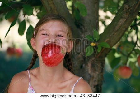 Fille de mordre dans une pomme sous un pommier